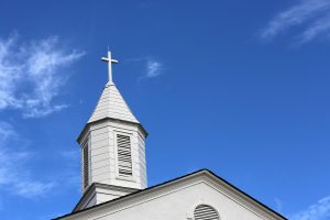 white steeple against blue sky with white clouds